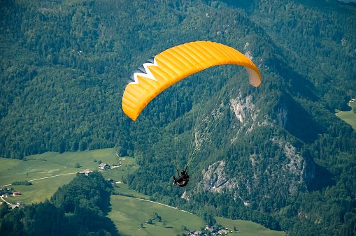 A paraglider flying over a beautiful alpine town and a lake next to it.