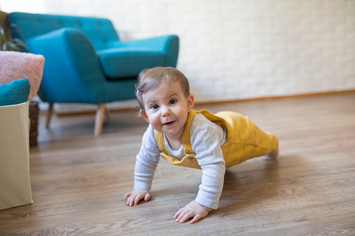 Cute baby girl crawling on floor in yellow