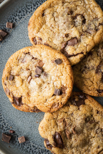 Four freshly baked chocolate chip cookies on ceramic plate