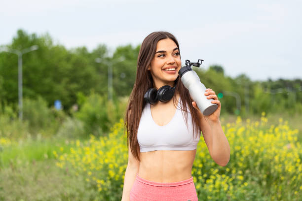 istock Beautiful sporty woman drinking water while resting from exercise. Beautiful female runner standing outdoors drinking water from her bottle. Fitness woman taking a break after running workout. 1248462603