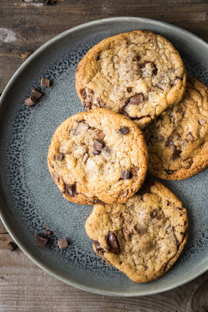 istock Four freshly baked chocolate chip cookies on ceramic plate 1248462642