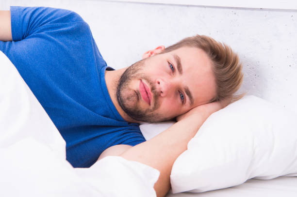 Happy man waking up and stretching in bed after a good night's sleep
