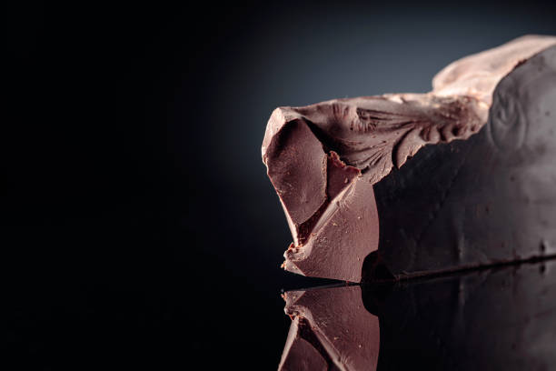 istock Piece of dark bitter chocolate on a black reflective background. 1248467298