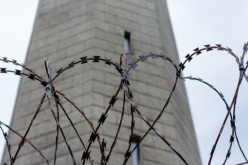barbed wire fence in front of a gray old tower
