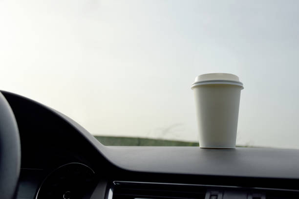 istock Paper coffee cup on the vehicle dashboard view from inside the vehicle 1248470438
