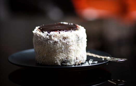 Coconut cake with chocolate topping named Ruske kape on a plate on dark table