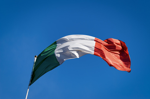 Close-up of a national Italian flag waving in the clear blue sky, photographed from below