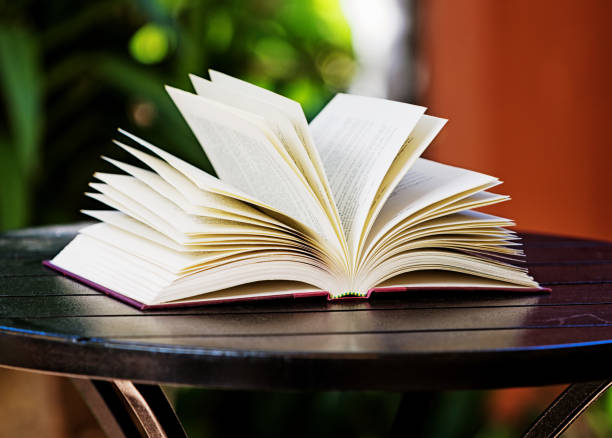 istock Open book resting on an outdoor table in a tranquil idyllic scene 1248484842