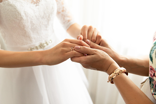 Bride and mother holding hands at wedding day