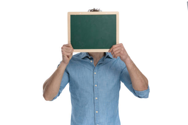 istock young casual guy in denim shirt hiding behind blackboard 1248489637