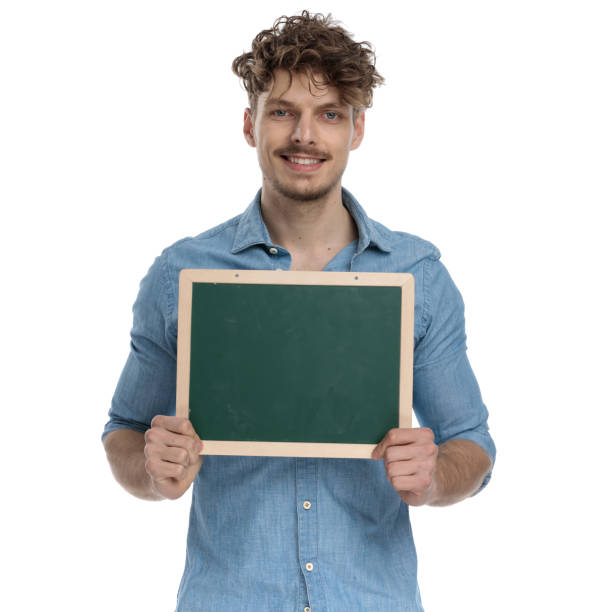 istock happy young casual guy holding blackboard and smiling 1248492107