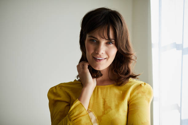 istock Young brunette woman standing by a window at home and smiling 1248493082