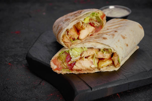 istock Wrap with fried chicken, vegetables and sauce isolated on dark  background 1248498475
