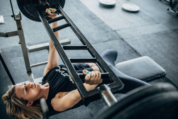 istock Strong female exercising bench press in gym 1248498511