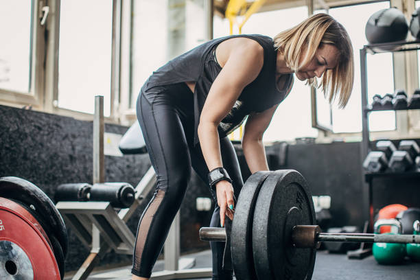 istock Strong female putting weights on barbell before training in gym 1248498805