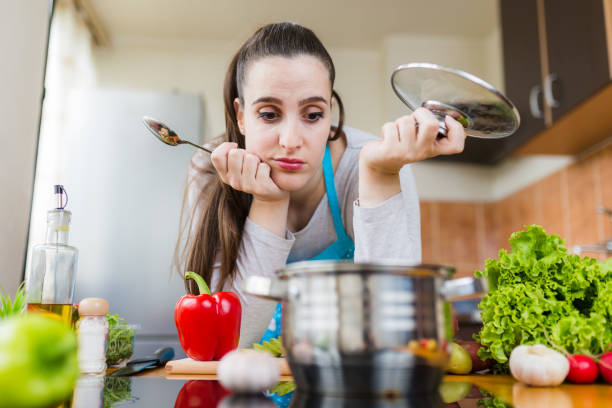 femme au foyer insatisfaite essayant de préparer le repas sain. problèmes d’apprentissage de la cuisine. - cooking fail photos et images de collection