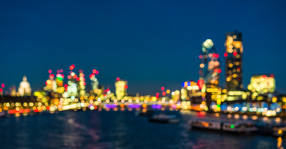 A panoramic view of central London, defocused in camera, from a bridge over the River Thames, with the City of London towards the left of the image, and buildings of the South Bank on the right.
