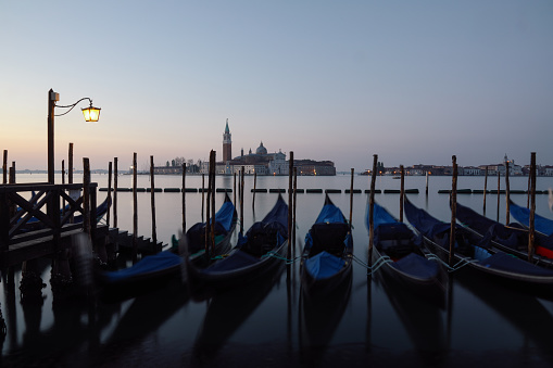 Long exposure of Venice, Italy with anchored gondolas on the Grand Canal at sunrise.