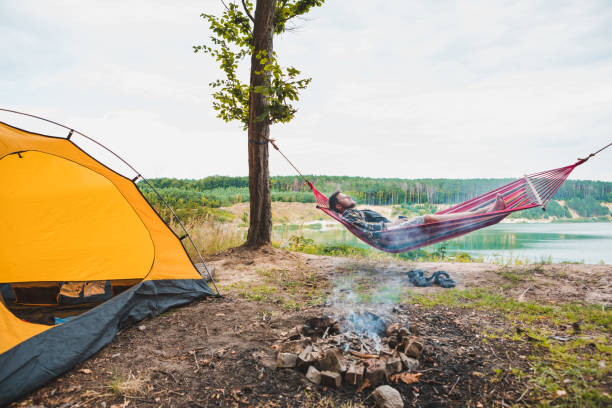 istock man laying on hammock at lake beach near camp fire 1248504144