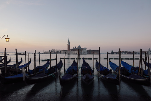 Venice, Veneto - Italy - 06-10-2021: Gondoliers near moored gondolas on the bustling Grand Canal, Venice