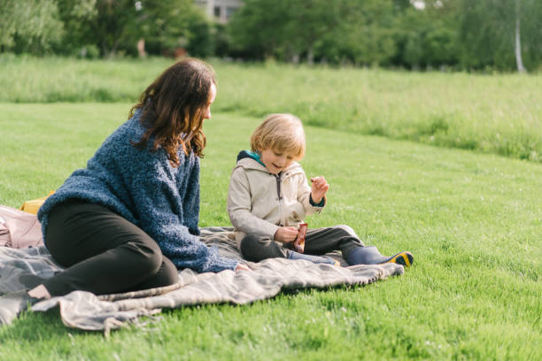 istock Boy sharing candy with woman sitting on the grass 1248508010