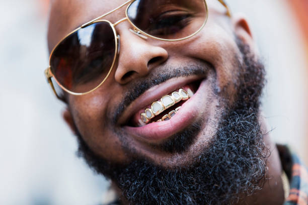 African-American man with gold grill An African-American man with a gold grill, thick beard and sunglasses, smiling. rap stock pictures, royalty-free photos & images