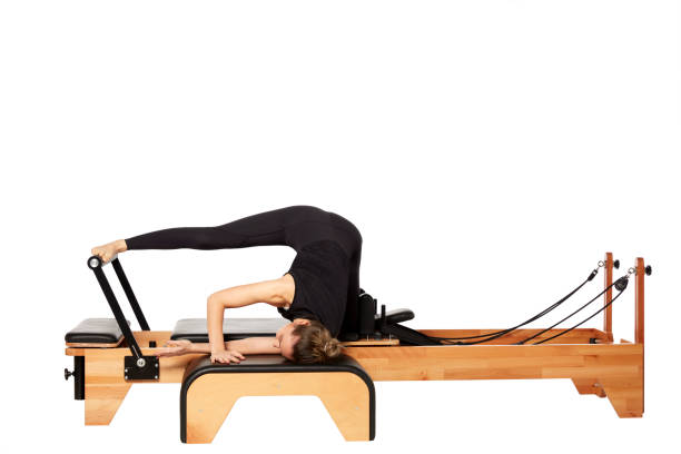 istock Young woman exercising on a Pilates machine on white background 1248513887