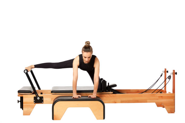 istock Young woman exercising on a Pilates machine on white background 1248513950