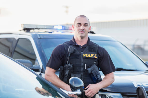 istock Policeman wearing bulletproof vest, by patrol car 1248514546
