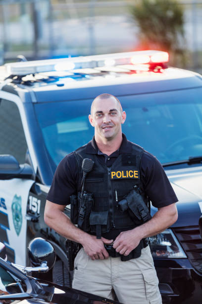 istock Policeman wearing bulletproof vest, by patrol car 1248514664