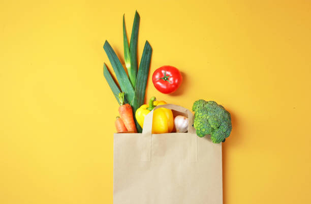 istock Vegetables in paper bag on yellow background. 1248521436