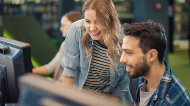 istock University Library: Bright Caucasian Girl and Talented Boy Study for Exams, Work on Assignment, Use Computer, Point at Screen,Talk, Look for Solution, Explain Subject. College Students Work Together 1248521654