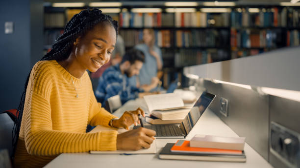 istock University Library: Gifted Black Girl uses Laptop, Writes Notes for the Paper, Essay, Study for Class Assignment. Diverse Multi-Ethnic Group of Students Learning, Studying for Exams, Talk in College 1248521751