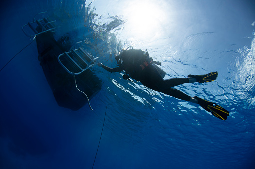 View of a female diver ending a dive and returning to the boat in Cayman Brac island - Cayman Islands