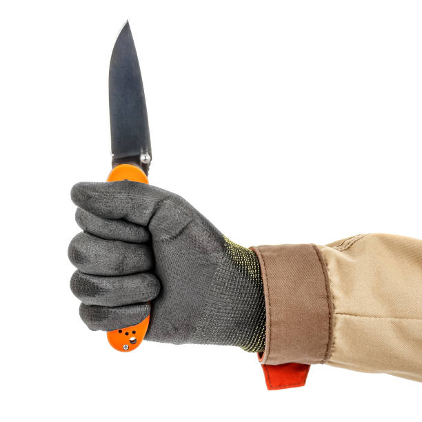 istock Open pocket folding knife with bright orange handle clenched in a worker fist in black protective glove isolated on white background 1248524611
