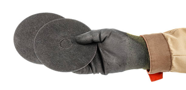 istock Worker hand in black protective glove and brown uniform holding two cutting abrasive discs for angle grinder isolated on white background 1248524624