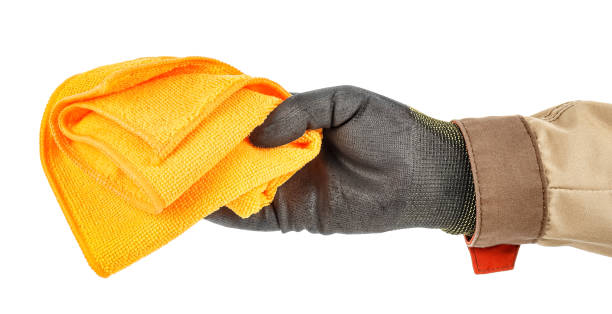 istock Worker hand in black protective glove and brown uniform holding unused orange microfiber cloth isolated on white background 1248524626