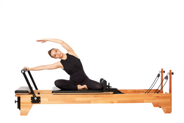 白い背景にピラティスマシンで運動若い女性 - pilates machine 写真 ストックフォトと画像