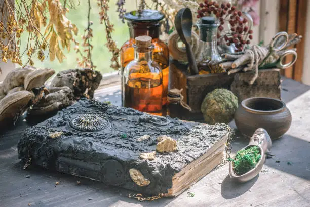 Magic potion bottles, spell book and dried plants on the witch doctor table. Witchcraft.