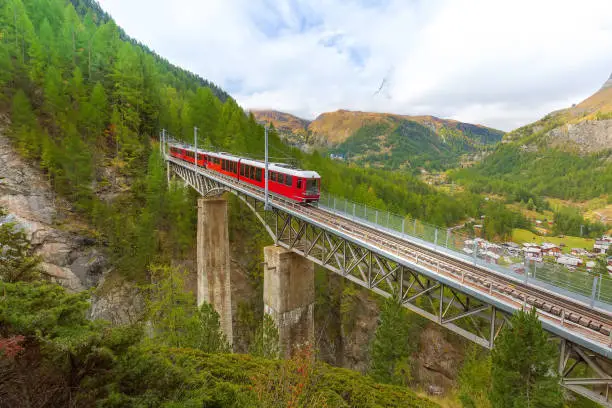 Zermatt, Switzerland. Gornergrat red tourist train on the bridge and Matterhorn peak panorama in Swiss Alps