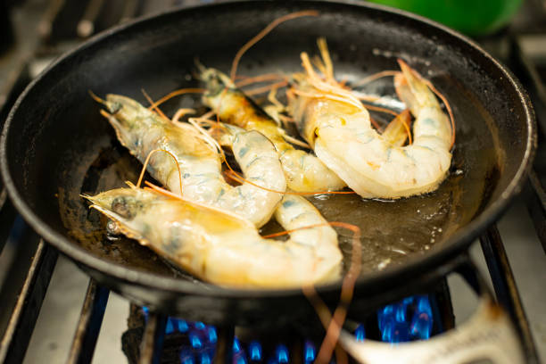 Image of raw shrimp on a frying pan over a gas stove burner
