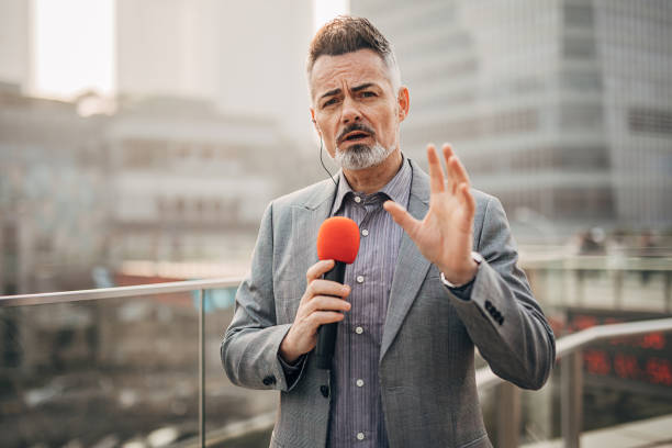Handsome male reporter in live broadcasting relays today's news One handsome male reporter in live broadcasting relays today's news. newscaster stock pictures, royalty-free photos & images