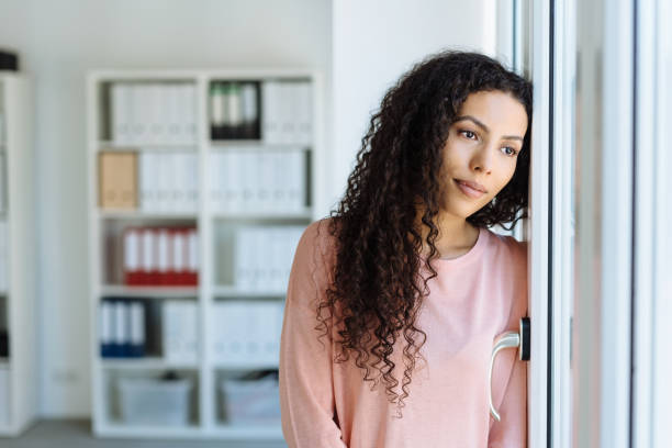 istock Young woman staring longingly through a window 1248531174