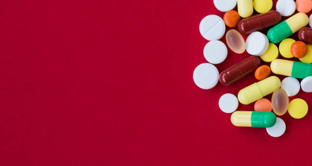 istock Medical background with pills and capsule on red background.Assorted pharmaceutical medicine pills, tablet. Heap of various assorted medicine tablets and pills different colors. Health care. Top view 1248537522
