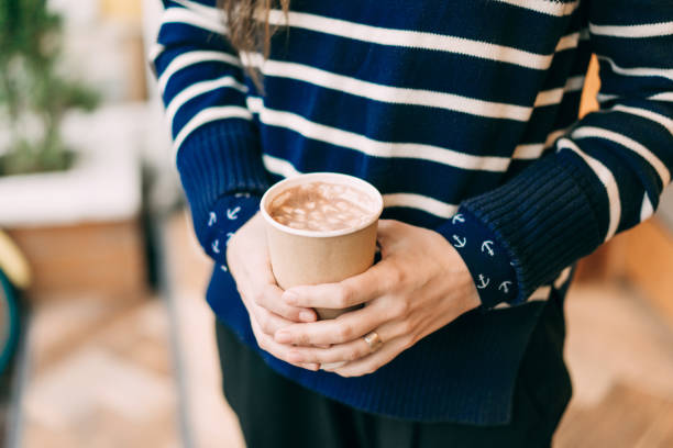 Close up of girl holding mug with cocoa and marshmallows