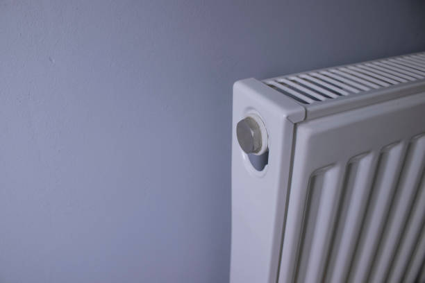 istock close up of Modern radiator on grey wall indoors. Central heating system 1248537906