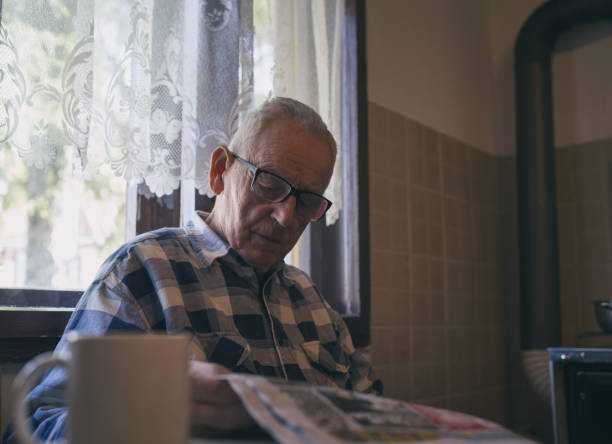istock Old man reading paper at home 1248538523