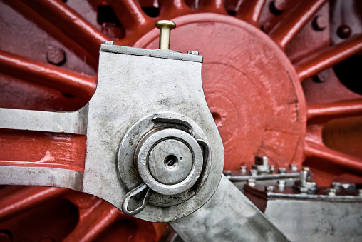 Detail of wheel and coupling rods of an old steam locomotive with textured metal surface and bolts.
