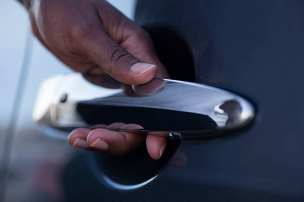 Close up image of driver's / passenger's left-hand opening / closing a car door, touching, holding, pulling a vehicle door handle.