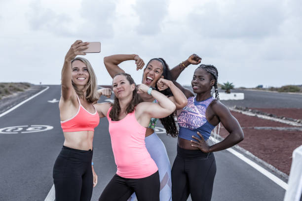 istock Multiracial sportswomen showing biceps and taking selfie 1248544028